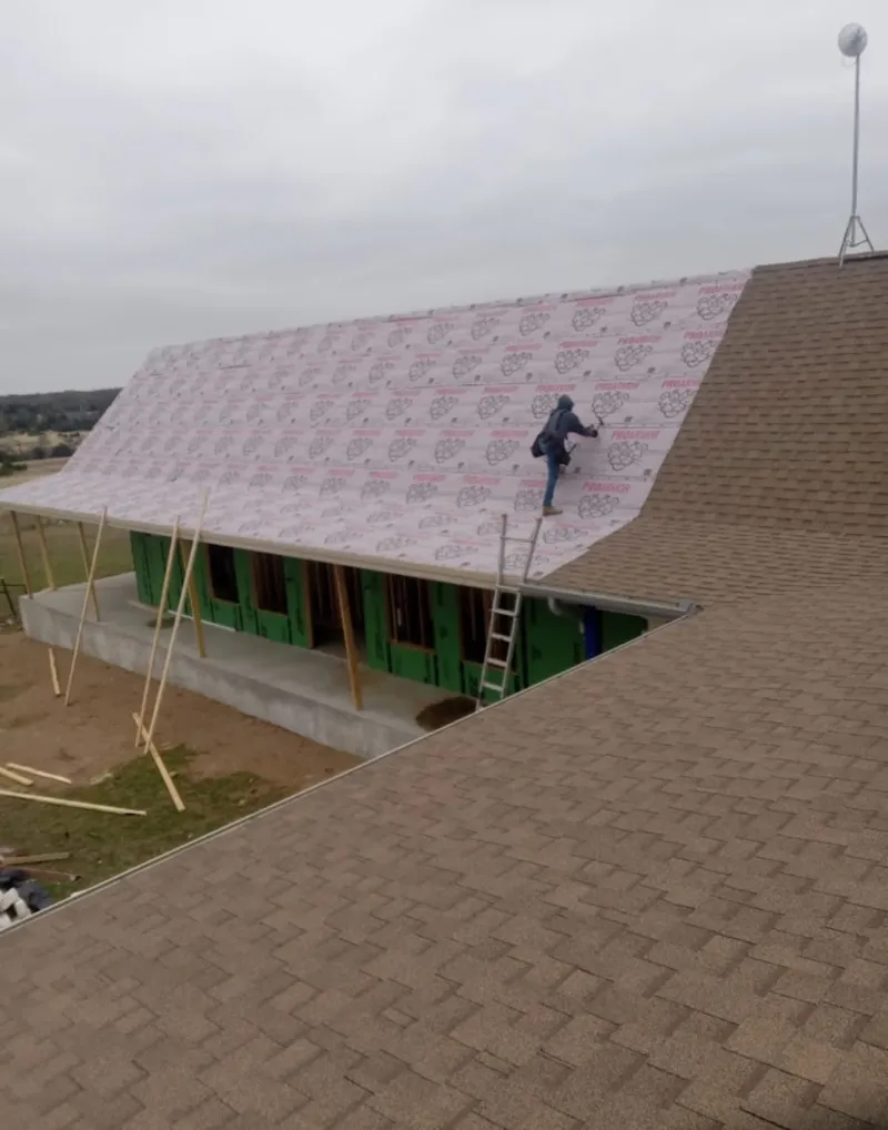 Worker preparing underlayment for a metal roof installation in Pismo Beach